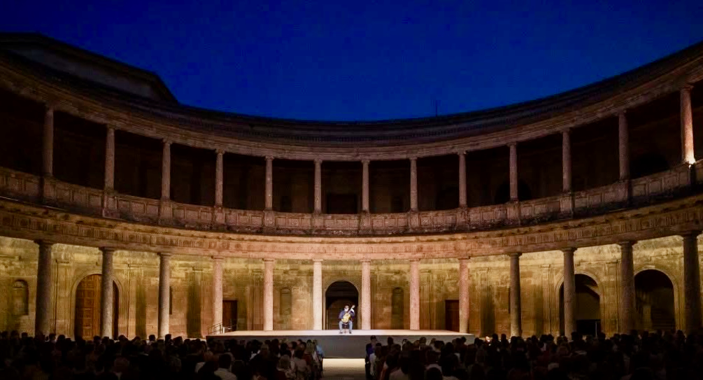 Jacob Kellermann performing on the stage in the courtyard of the Palacio de Carlos V, Alhambra, before a full audience at dusk